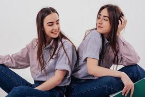 belles filles. Deux soeurs jumelles assis et posant dans le studio avec un fond blanc photo