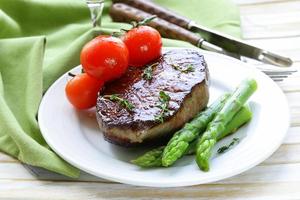 steak de boeuf grillé avec garniture de légumes (asperges et tomates)