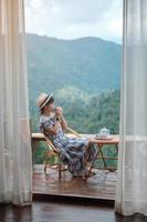 femme buvant du thé et regardant la montagne, jeune blogueur séjournant à la campagne chez l'habitant le matin.voyage, vacances, voyage, voyage et concept de détente photo