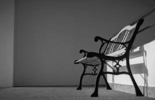 banc en fer forgé vide placé près des escaliers du bâtiment. soleil dans le bâtiment en béton. concept déprimé, triste et solitaire. un banc en fer forgé vide. mobilier d'intérieur à l'appartement. photo