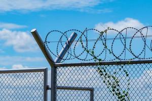 barrière de sécurité de la prison. clôture de sécurité en fil de fer barbelé. clôture de prison en barbelés. frontière barrière. mur de sécurité frontalier. prison pour arrêter des criminels ou des terroristes. zone privée. notion de zone militaire. photo