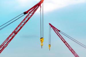 grue sur chenilles contre le ciel bleu et les nuages blancs. secteur immobilier. la grue sur chenilles rouge utilise un équipement de levage de bobine sur le chantier de construction. grue à louer. concessionnaire de grues pour les entreprises de construction. photo