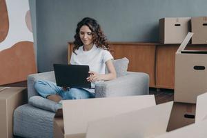 une femme heureuse est assise dans un fauteuil et travaille avec un ordinateur. commande de service de livraison par internet. photo