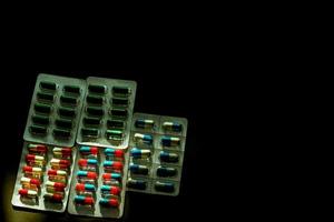 coloré de pilules de capsule antibiotique sous blister sur fond sombre avec espace de copie. médecine pour les maladies infectieuses. utilisation d'antibiotiques raisonnable. résistance aux médicaments et concept de soins de santé. photo