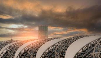 mise au point sélective sur le toit de l'aéroport et flou de la tour de contrôle du trafic aérien à l'aéroport contre un ciel nuageux sombre. structure en acier du toit de l'aéroport. architecture de bâtiment extérieur avec un design moderne géométrique. photo