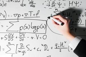 homme écrivant des formules mathématiques complexes sur tableau blanc. mathématiques et sciences photo