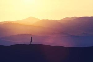 femme célibataire marchant sur la colline pendant le coucher du soleil. photo