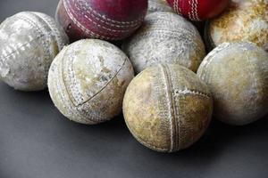 anciens équipements de sport de cricket d'entraînement sur sol sombre, balle en cuir, guichets, casque et chauve-souris en bois, mise au point douce et sélective, amateurs de sport de cricket traditionnels dans le monde entier. photo