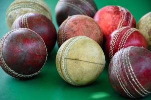 balles de cricket en cuir anciennes et utilisées en gros plan sur un sol vert, mise au point douce et sélective. concept pour les amateurs de cricket du monde entier. photo