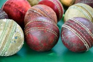balles de cricket en cuir anciennes et utilisées en gros plan sur un sol vert, mise au point douce et sélective. concept pour les amateurs de cricket du monde entier. photo