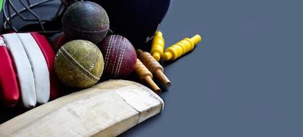 anciens équipements de sport de cricket d'entraînement sur sol sombre, balle en cuir, guichets, casque et chauve-souris en bois, mise au point douce et sélective, amateurs de sport de cricket traditionnels dans le monde entier. photo