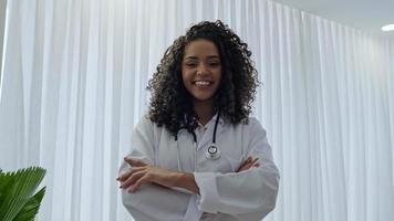 une jeune femme médecin latine porte un uniforme blanc, une blouse médicale blanche, un stéthoscope et regarde la caméra photo