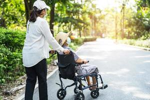 aide soignante et soins asiatiques seniors ou personnes âgées vieille dame patiente assise sur un fauteuil roulant et portant un masque facial pour voyager dans le parc, photo