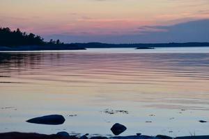 coucher de soleil violet bleu sur un lac dans l'archipel suédois photo