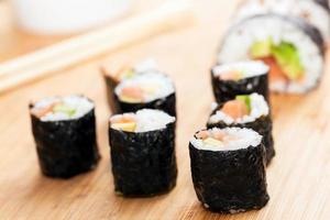 rouleaux de sushi au saumon, avocat, riz aux algues et baguettes photo