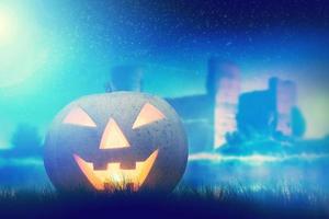 citrouille d'halloween rougeoyante dans un paysage sombre et brumeux avec château gothique et lune photo