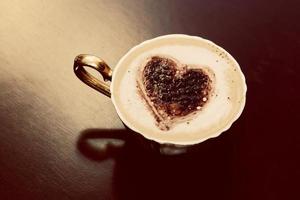 tasse de café en forme de coeur au chocolat sur mousse de lait. photo