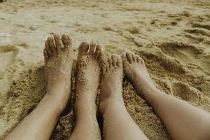 les pieds d'un couple sur la plage de sable blanc photo
