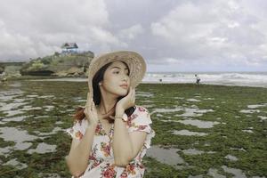 une jeune fille asiatique portant un chapeau de plage se détend sur la plage de ciel bleu à gunungkidul, indonésie photo