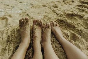 les pieds d'un couple sur la plage de sable blanc photo