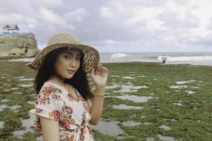 une jeune fille asiatique portant un chapeau de plage se détend sur la plage de ciel bleu à gunungkidul, indonésie photo