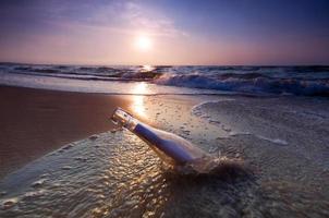 bouteille sur la plage au coucher du soleil photo