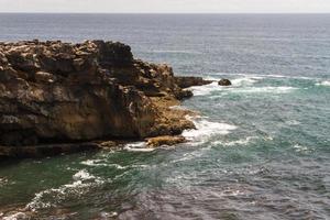 les vagues se battent sur la côte rocheuse déserte de l'océan atlantique, le portugal photo