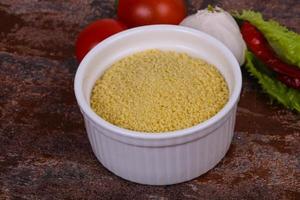 couscous cru dans le bol servi feuilles de salade, tomate et poivron photo