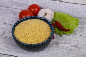 couscous cru dans le bol servi feuilles de salade, tomate et poivron photo