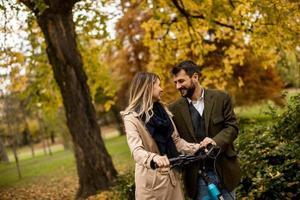 jeune couple dans le parc d'automne avec vélo électrique photo