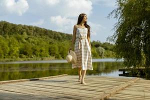 jeune femme marchant sur la jetée en bois au bord du lac calme photo