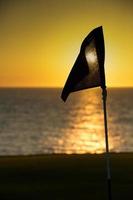 drapeau de terrain de golf qui se profile au coucher du soleil