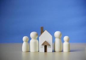 quatre personnages en bois debout à proximité d'une petite maison en bois. concept pour la famille, le prêt, l'échelle de propriété, la finance, l'hypothèque, l'investissement immobilier, les taxes et les bonus. photo