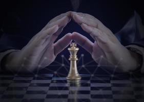 main d'homme d'affaires protège les échecs du roi d'or pour combattre les échecs du roi d'argent pour jouer avec succès dans la compétition avec le fond du réseau technologique. concept de stratégie de gestion ou de leadership. photo