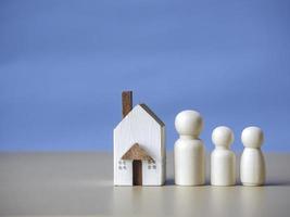 quatre personnages en bois debout à proximité d'une petite maison en bois. concept pour la famille, le prêt, l'échelle de propriété, la finance, l'hypothèque, l'investissement immobilier, les taxes et les bonus. photo