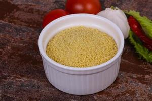 couscous cru dans le bol servi feuilles de salade, tomate et poivron photo