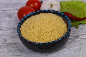 couscous cru dans le bol servi feuilles de salade, tomate et poivron photo