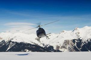un hélicoptère de sauvetage en montagne en vol par des montagnes enneigées photo