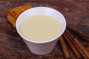 lait concentré dans le bol avec sinnamon et pâtisserie photo