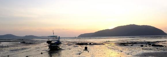 bateau sur la plage le matin avant le lever du soleil derrière la montagne photo