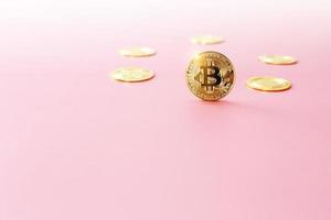 gros plan pièce de monnaie bitcoin dorée sur fond rose clair. symbole de crypto-monnaie. la pièce d'or bitcoin brillante se démarque devant les autres pièces avec espace de copie. photo