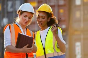 femme d'affaires et travailleuse logistique vérifiant la boîte des conteneurs et chargeant les produits dans l'ordinateur depuis le navire de fret au conteneur de fret. photo