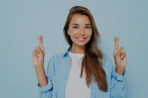 femme joyeuse dans des vêtements décontractés pointe vers le haut les doigts croisés photo