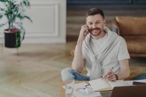 homme d'affaires heureux parlant au téléphone tout en étant assis à son bureau au bureau à domicile photo