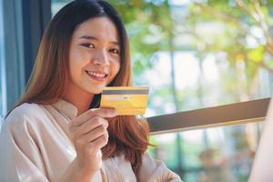 jeune femme saisissant le numéro de carte de crédit sur un ordinateur portable faisant des achats en ligne à la maison. mise au point sélectionnée photo