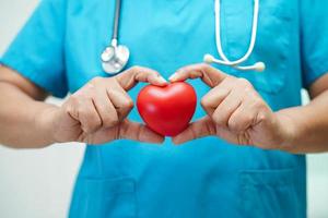 femme médecin asiatique tenant un coeur rouge pour la santé à l'hôpital. photo