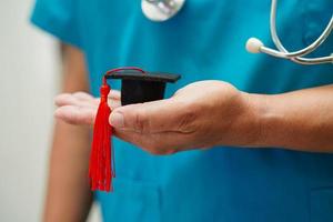 femme médecin asiatique tenant un chapeau de graduation à l'hôpital, concept d'éducation médicale. photo
