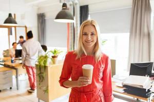 heureuse femme créative avec une tasse de café au bureau