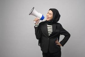 une femme musulmane heureuse annonce avec un mégaphone sur fond blanc