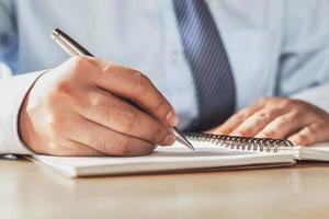 homme d'affaires écrivant sur un carnet de notes au bureau photo